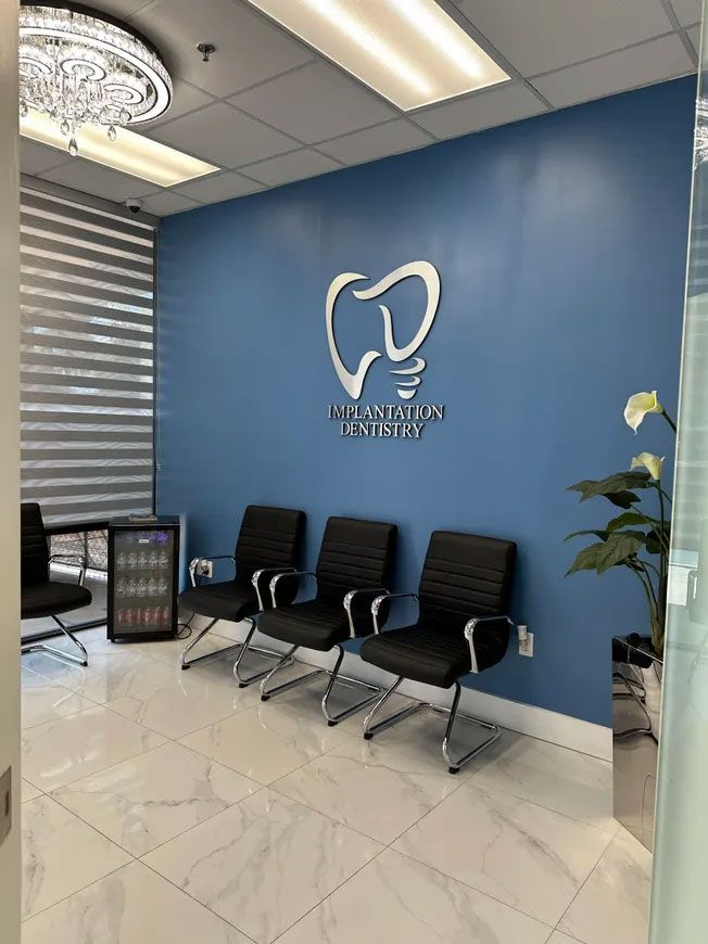 Dental office waiting room with blue wall, chairs, and logo.