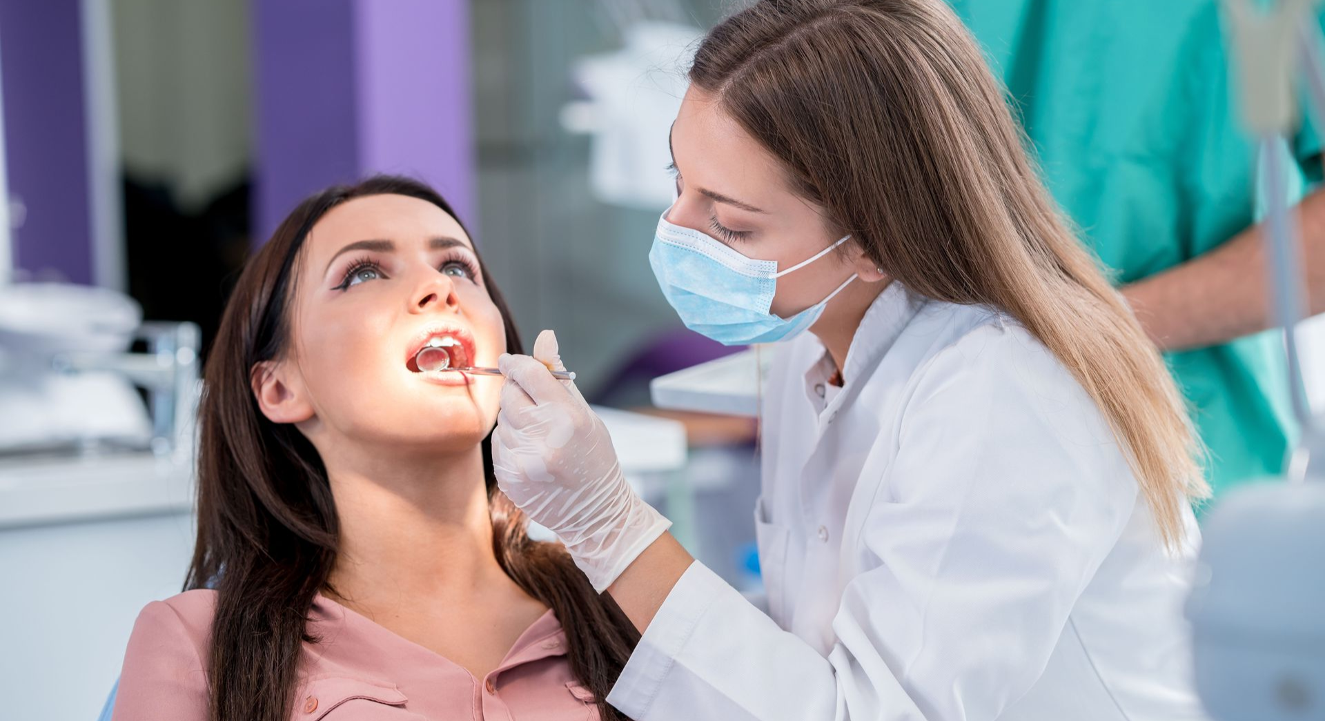 Dentist examining a patient's mouth with tools in a dental office.