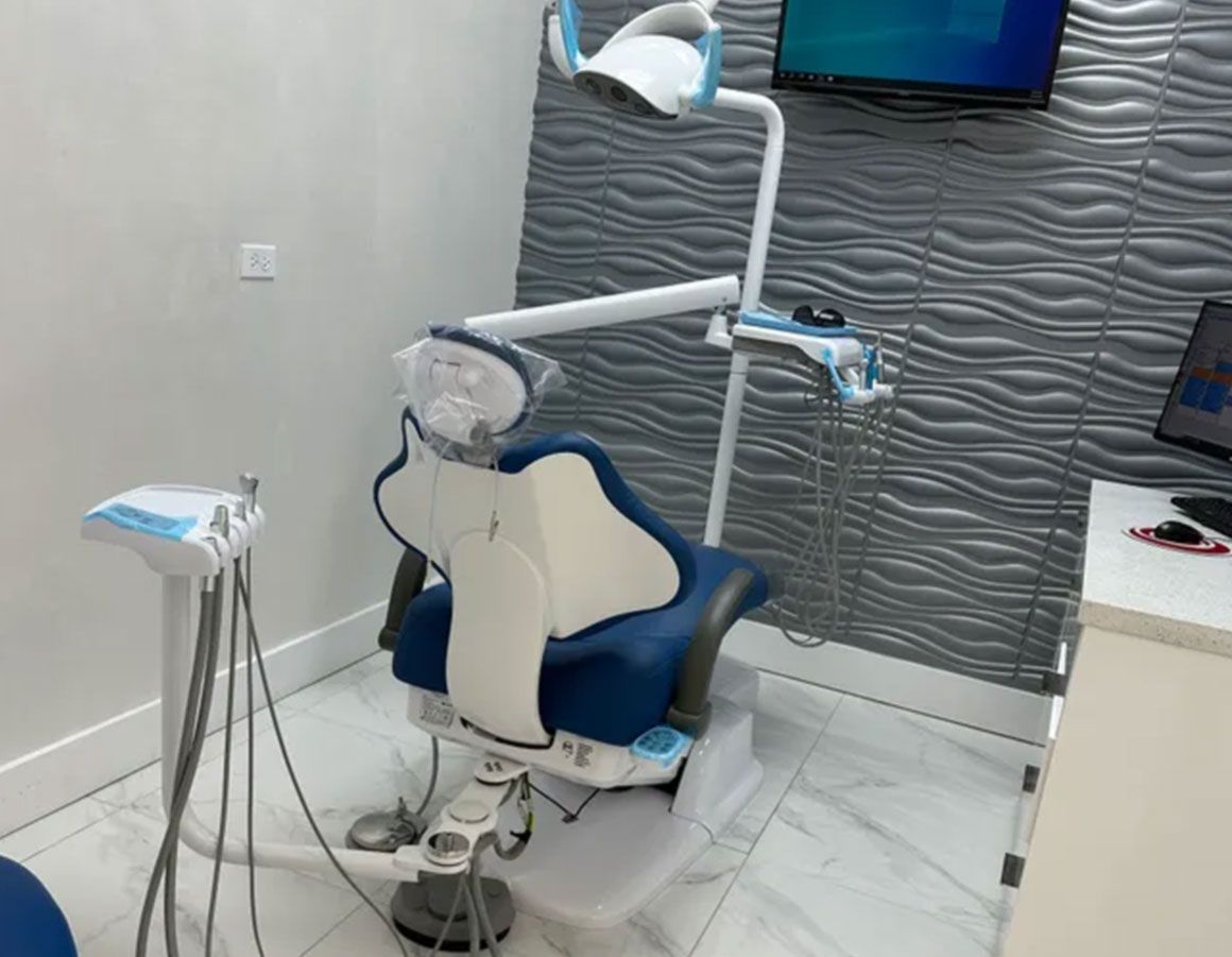 Dental chair in a modern room, with attached light and tools. Blue and white colors, bright setting.