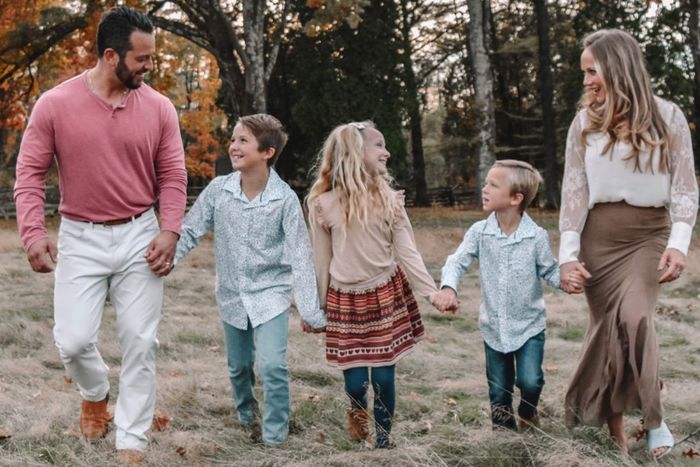 A family is walking through a field holding hands.