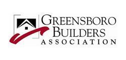 The logo for the greensboro builders association has a house and a check mark.