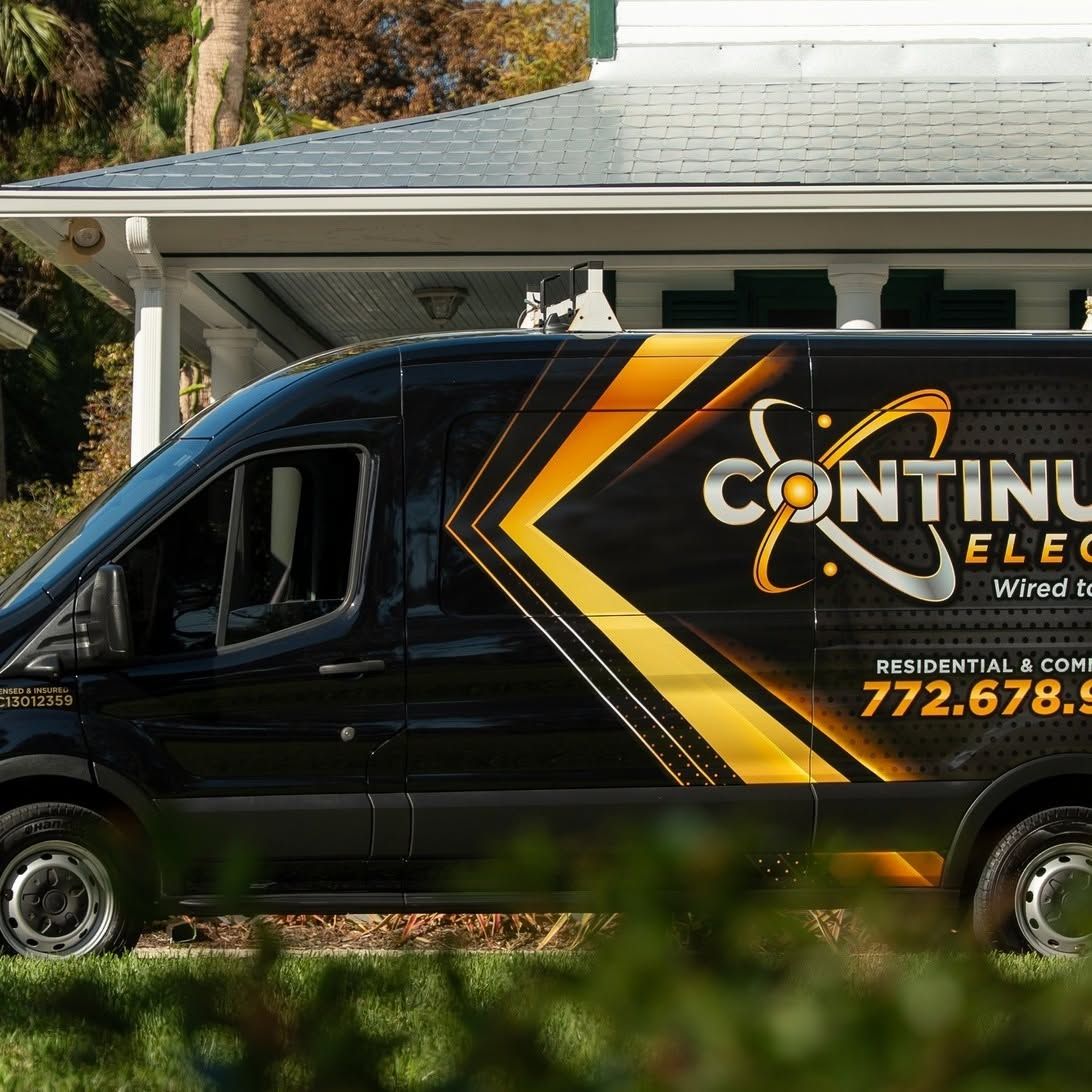 Black Continuum Electric service van parked in front of a house with bold yellow graphics