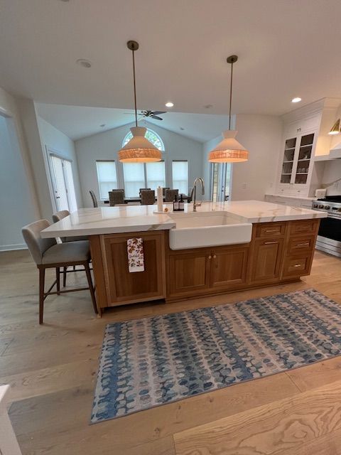 Modern kitchen with a large wood island, white farmhouse sink, two hanging pendant lights, and blue patterned floor rug.