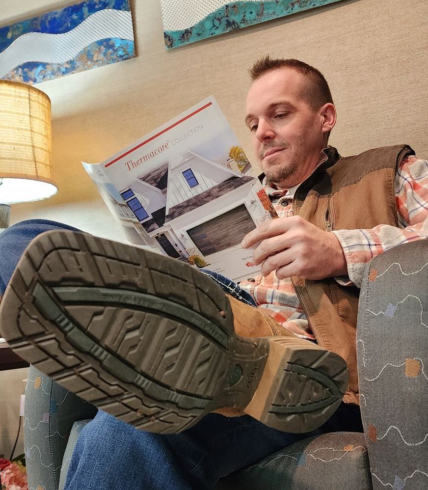 A man is sitting in a chair reading a magazine.