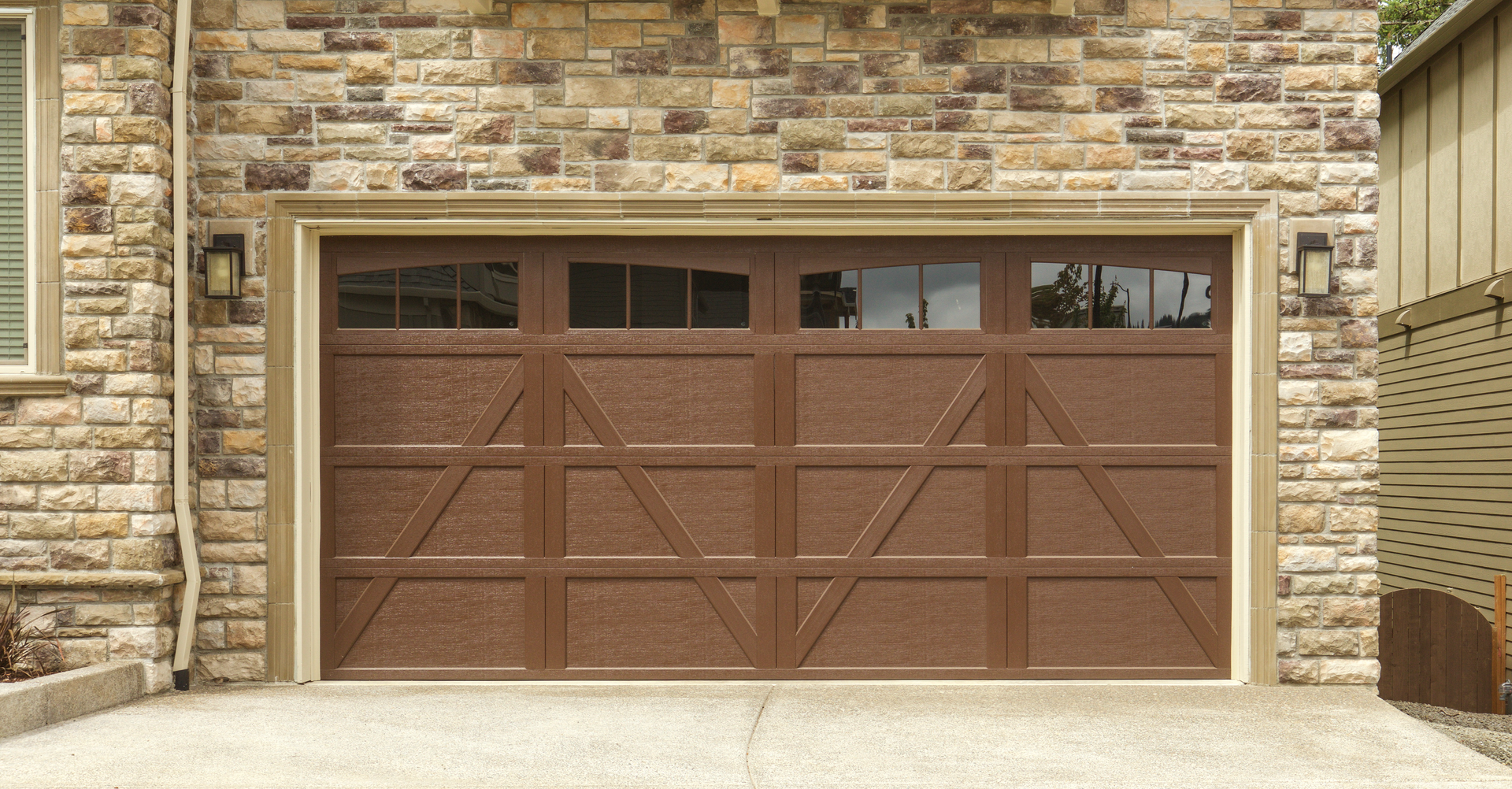 A brown garage door is sitting in front of a brick building.