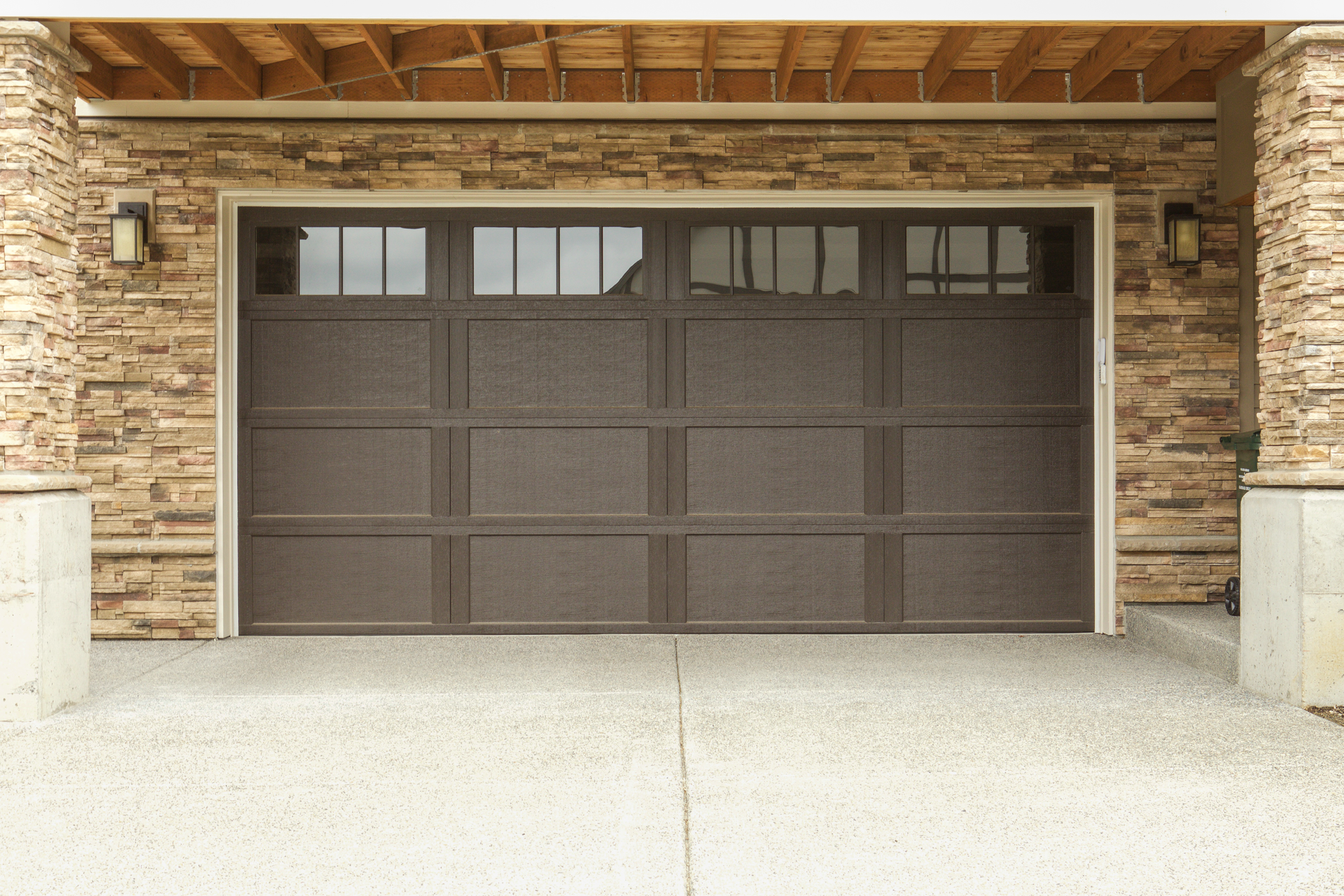 A brown garage door with a stone wall behind it