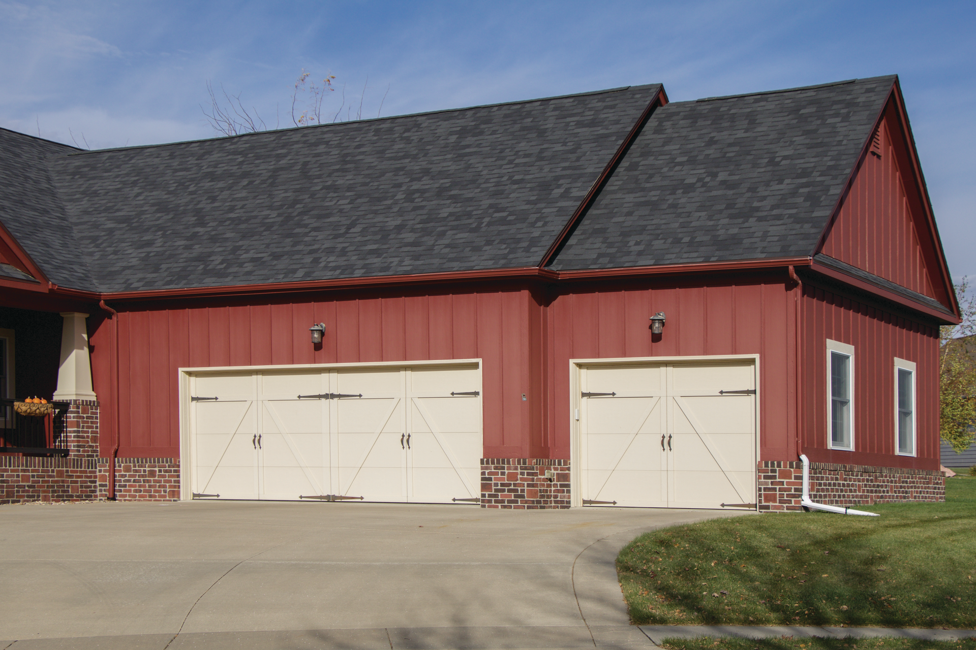 A red barn with two white garage doors and a gray roof