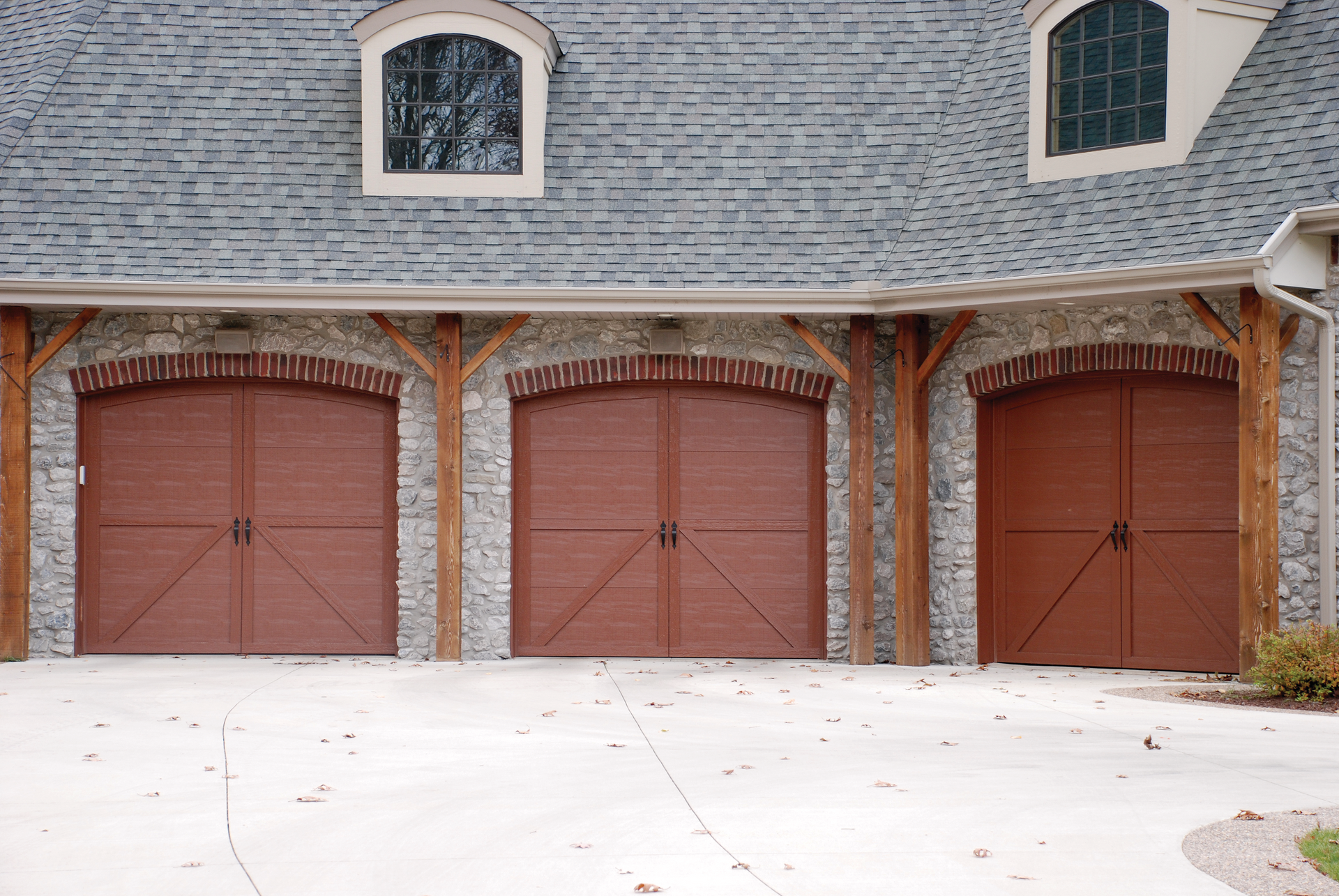 A row of brown garage doors on the side of a house