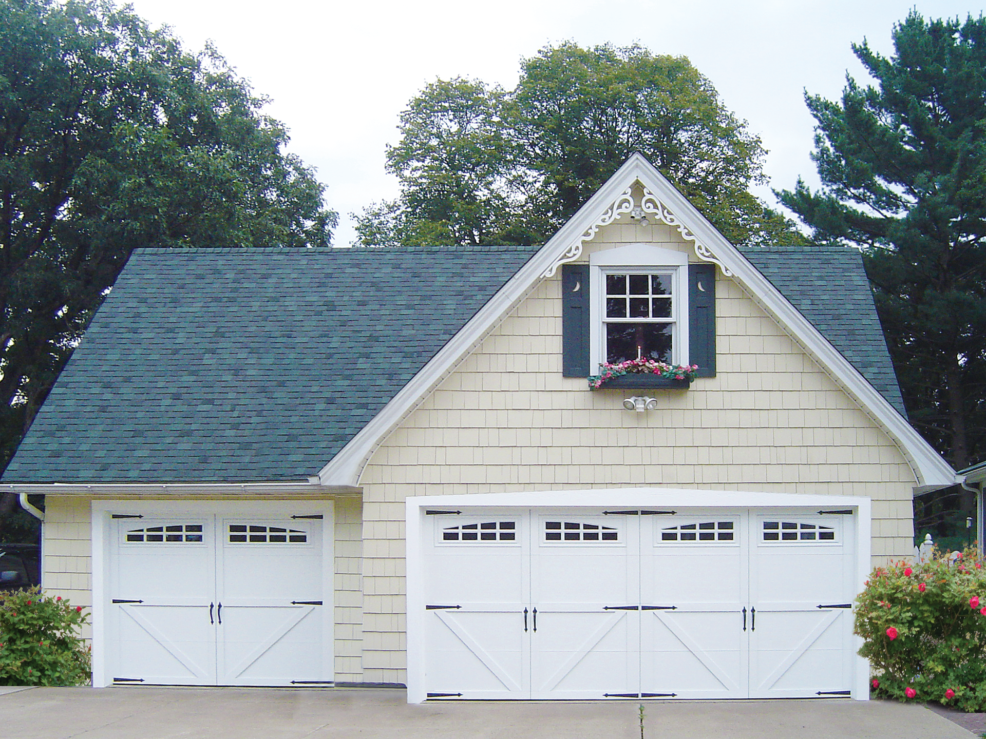 A white house with a blue roof and white garage doors