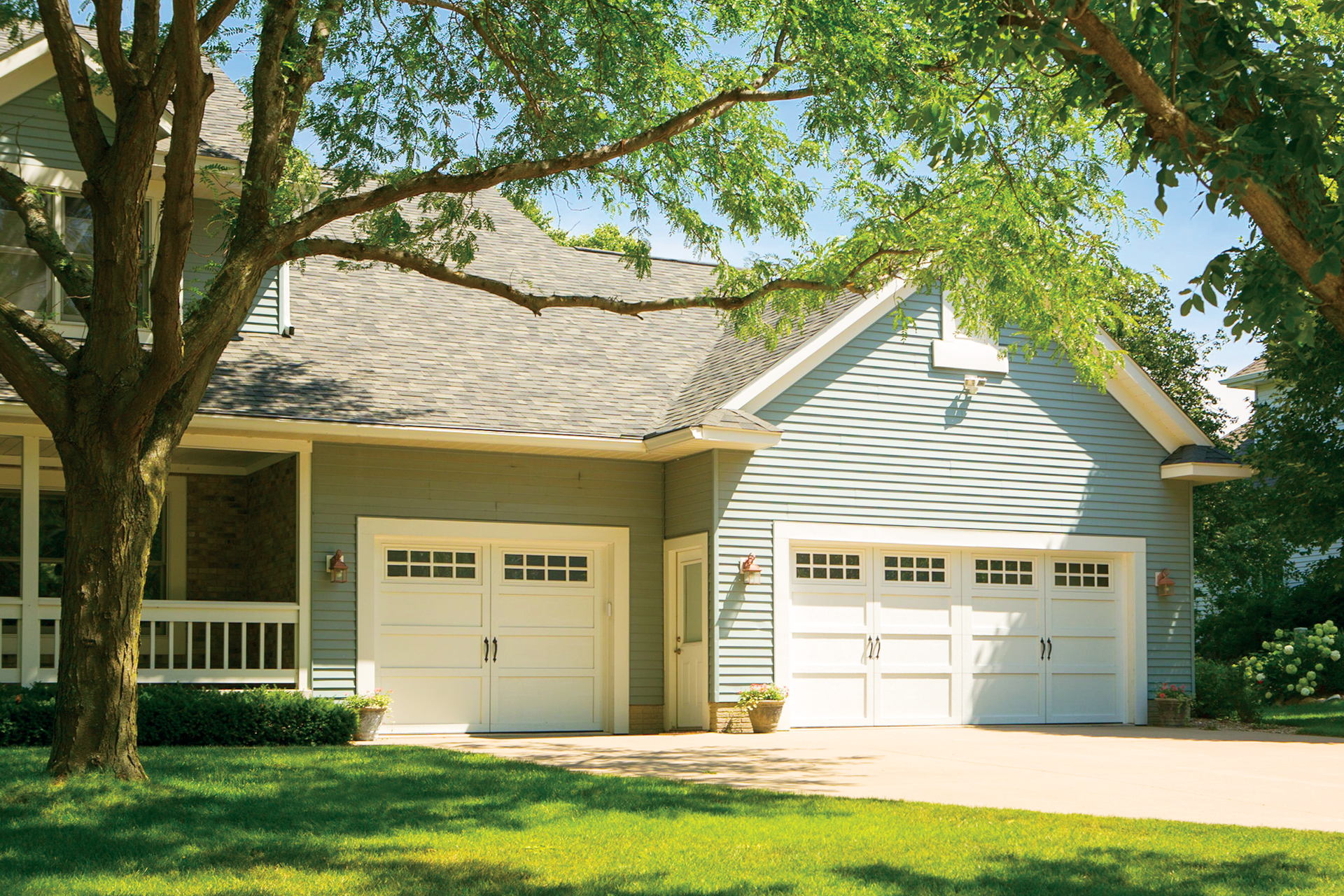 A house with two garage doors and a tree in front of it