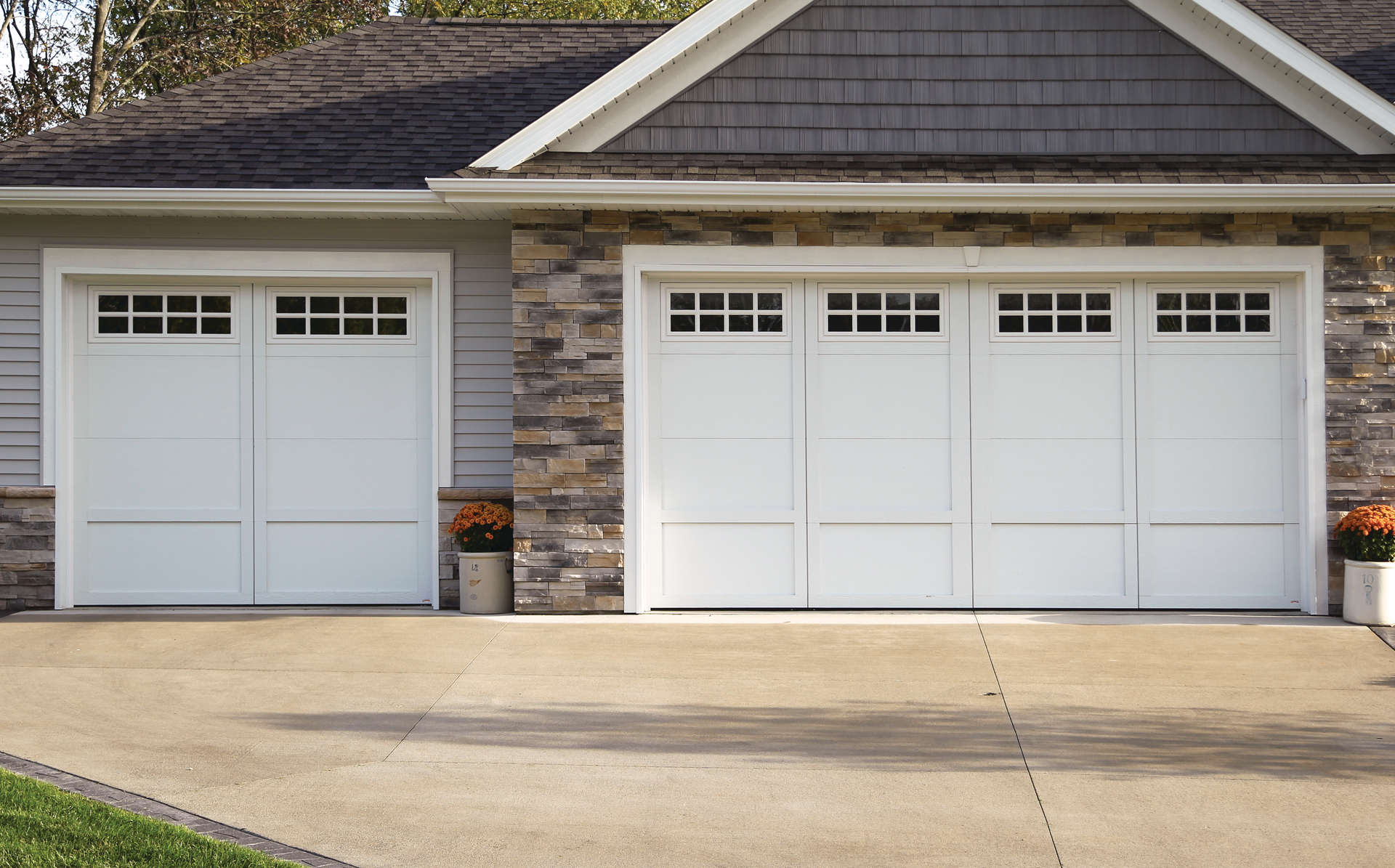 A house with three white garage doors and a driveway.