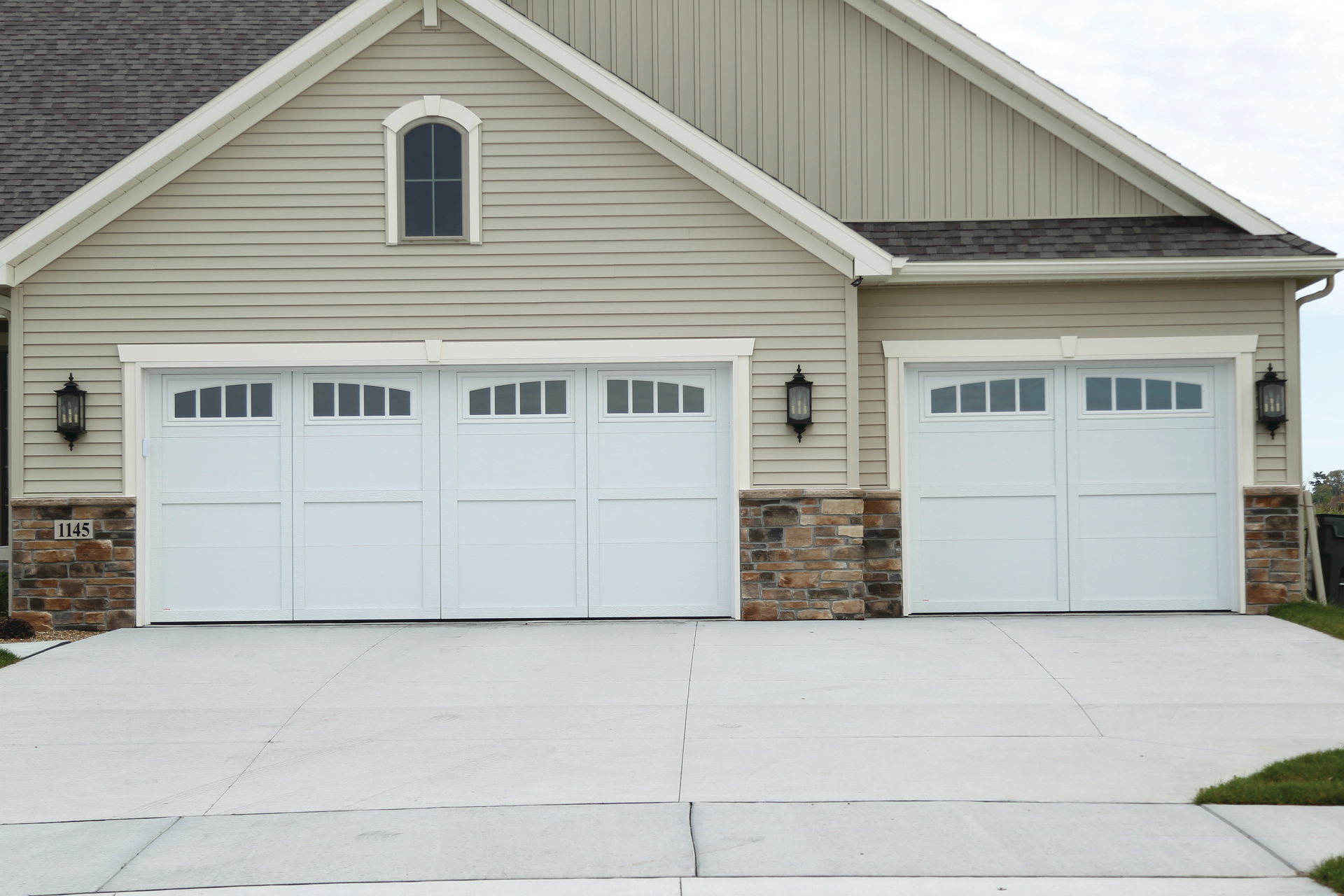 A house with three garage doors and a concrete driveway