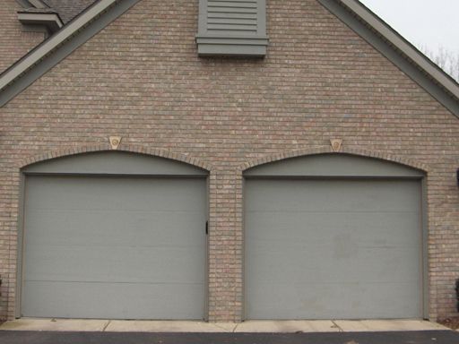 A brick building with two garage doors and arched windows