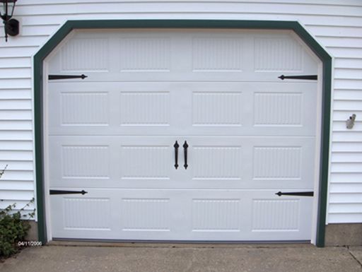 A white garage door with black hinges and a green trim