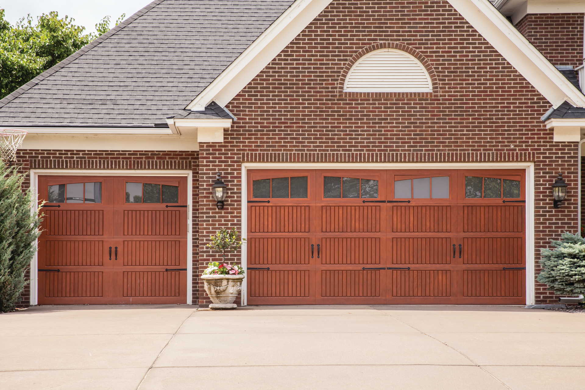 There are two garage doors on the side of a brick house.