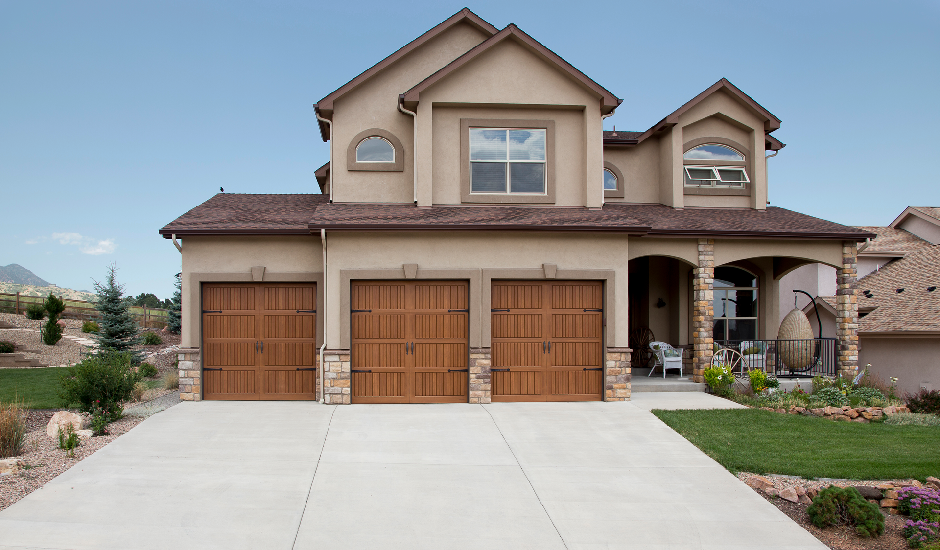 A large house with three garage doors and a concrete driveway