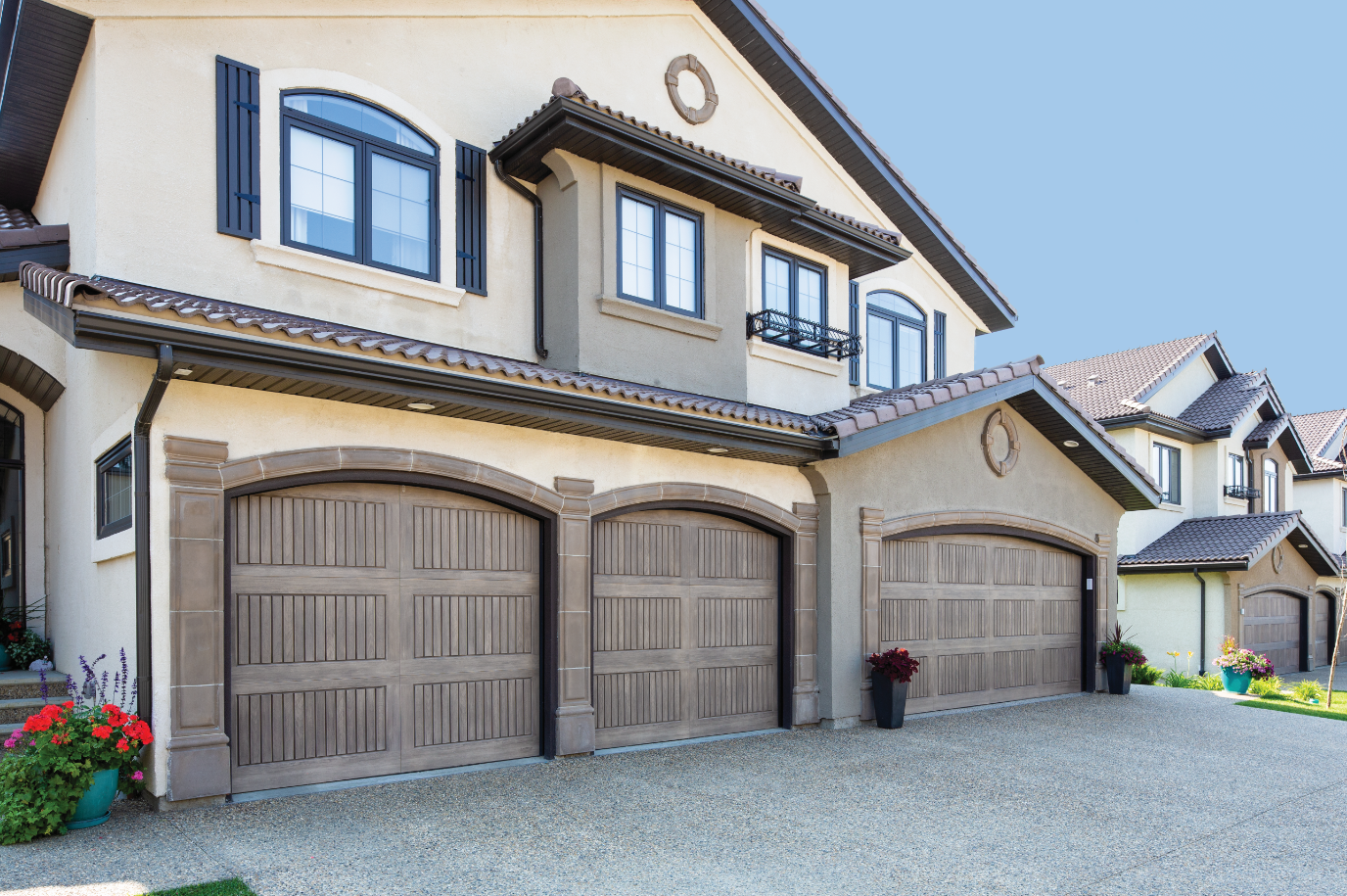 A large house with three garage doors and a lot of windows.