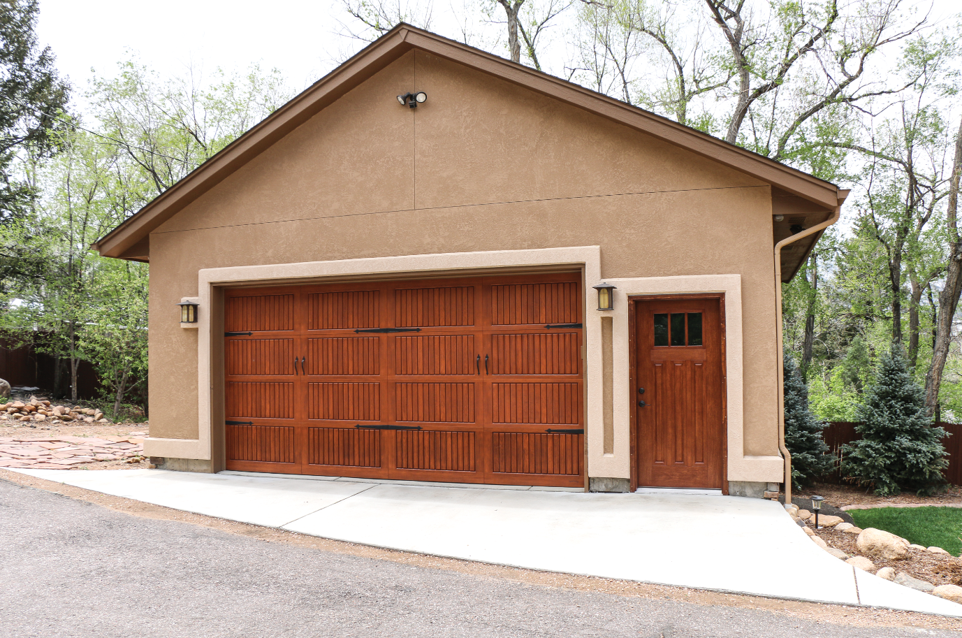 A garage with two wooden garage doors and a concrete driveway.