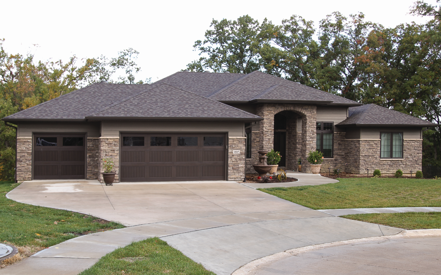 A large house with a gray roof and brown garage doors