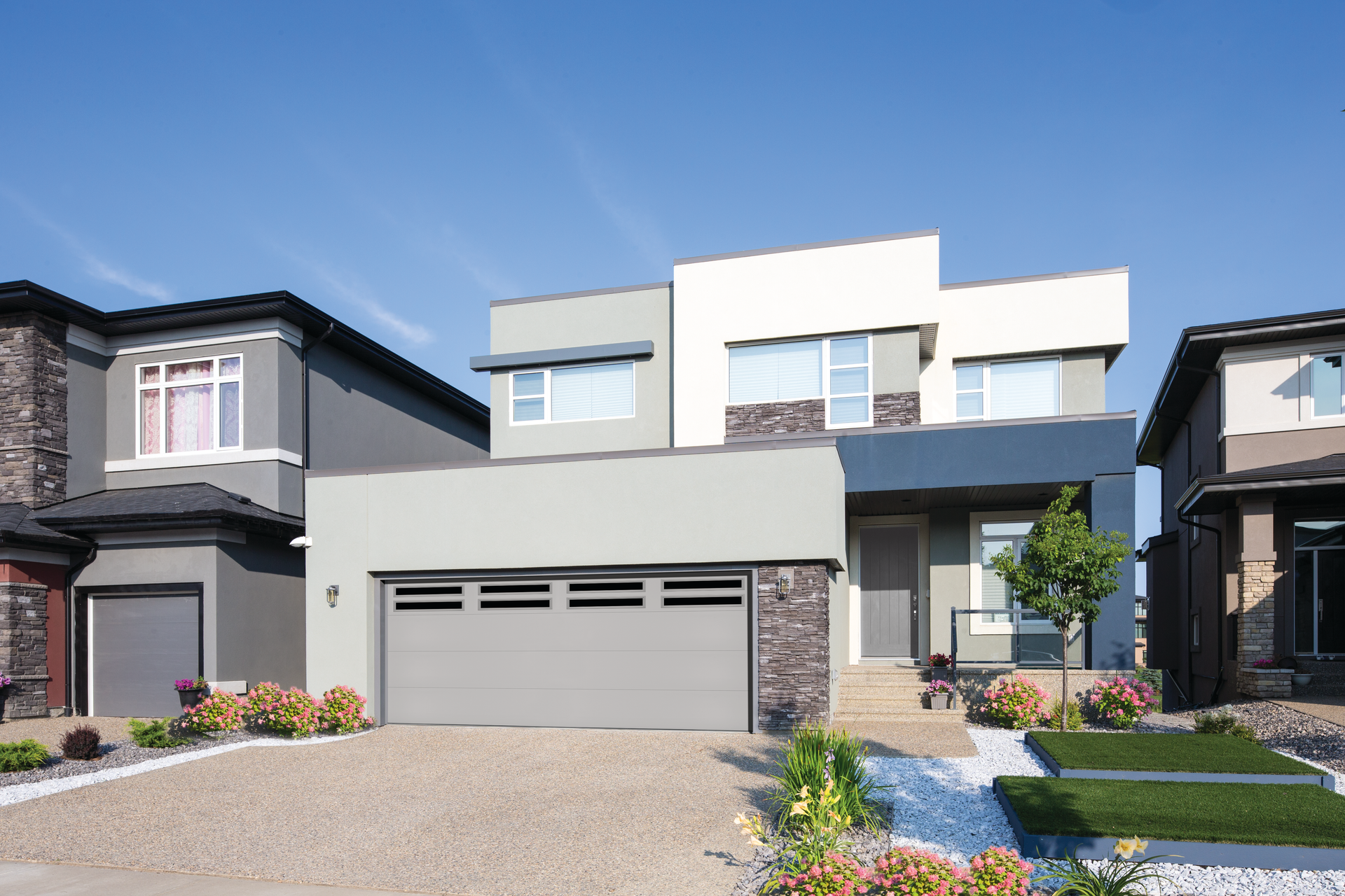 A house with a gray garage door is surrounded by other houses