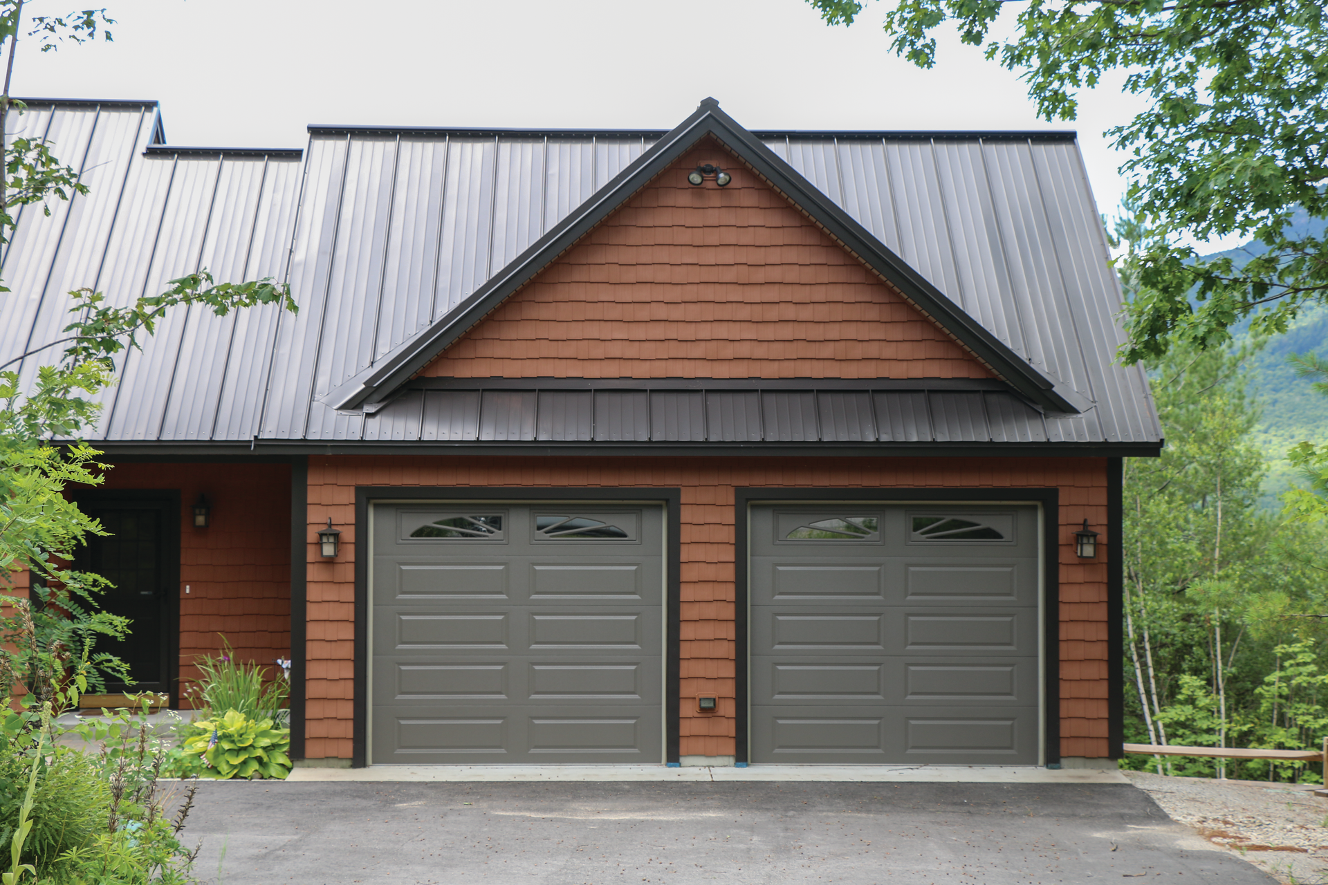 A house with two garage doors and a black roof