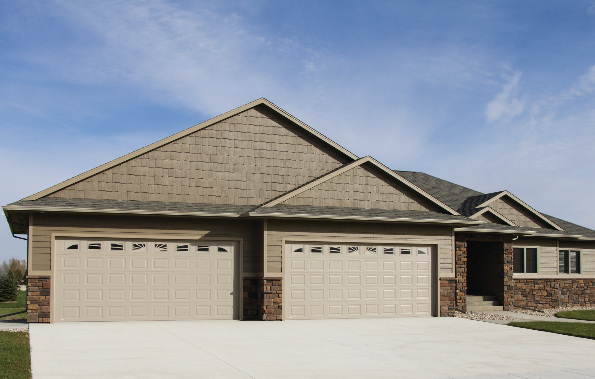 A house with three garage doors and a blue sky in the background