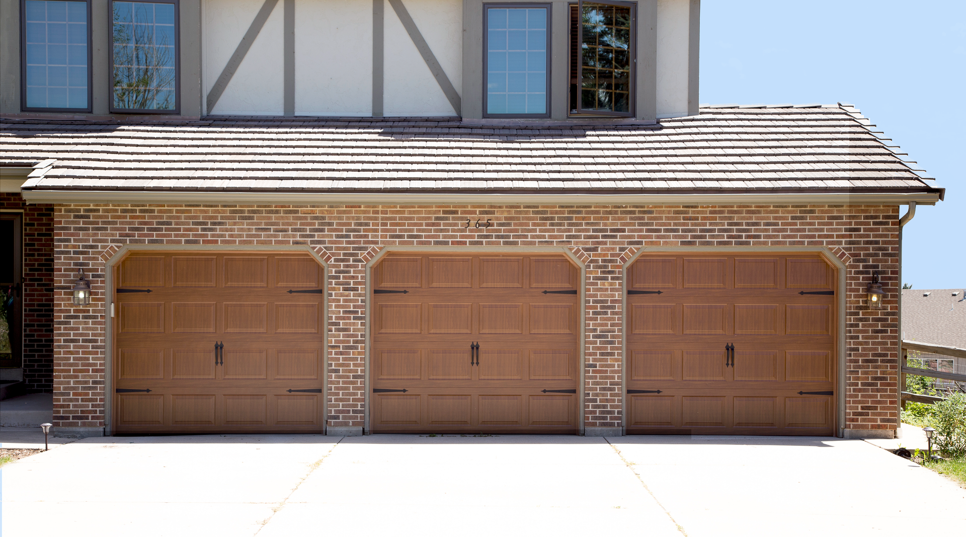 A brick house with three garage doors and a roof