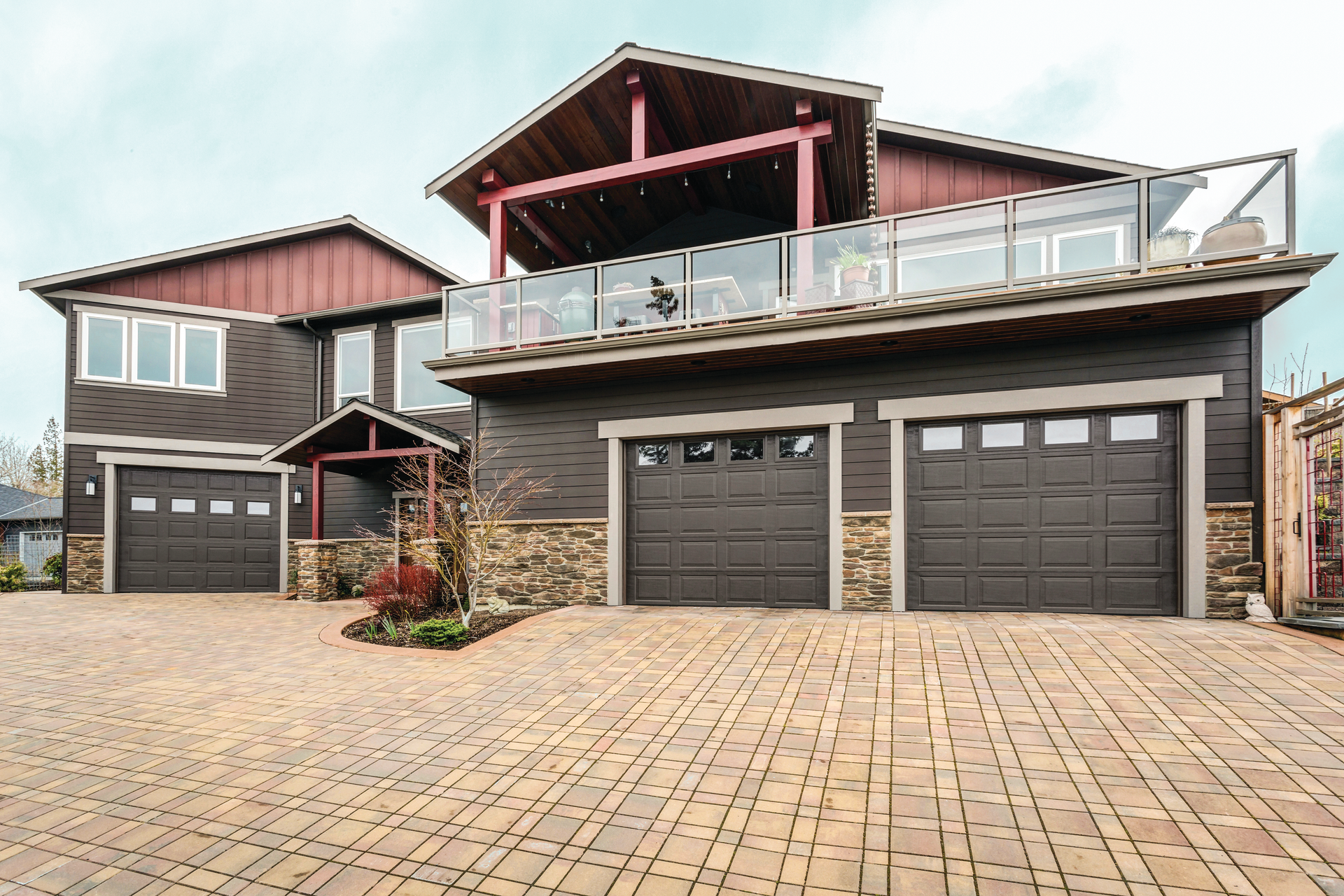 A large house with three garage doors and a balcony.