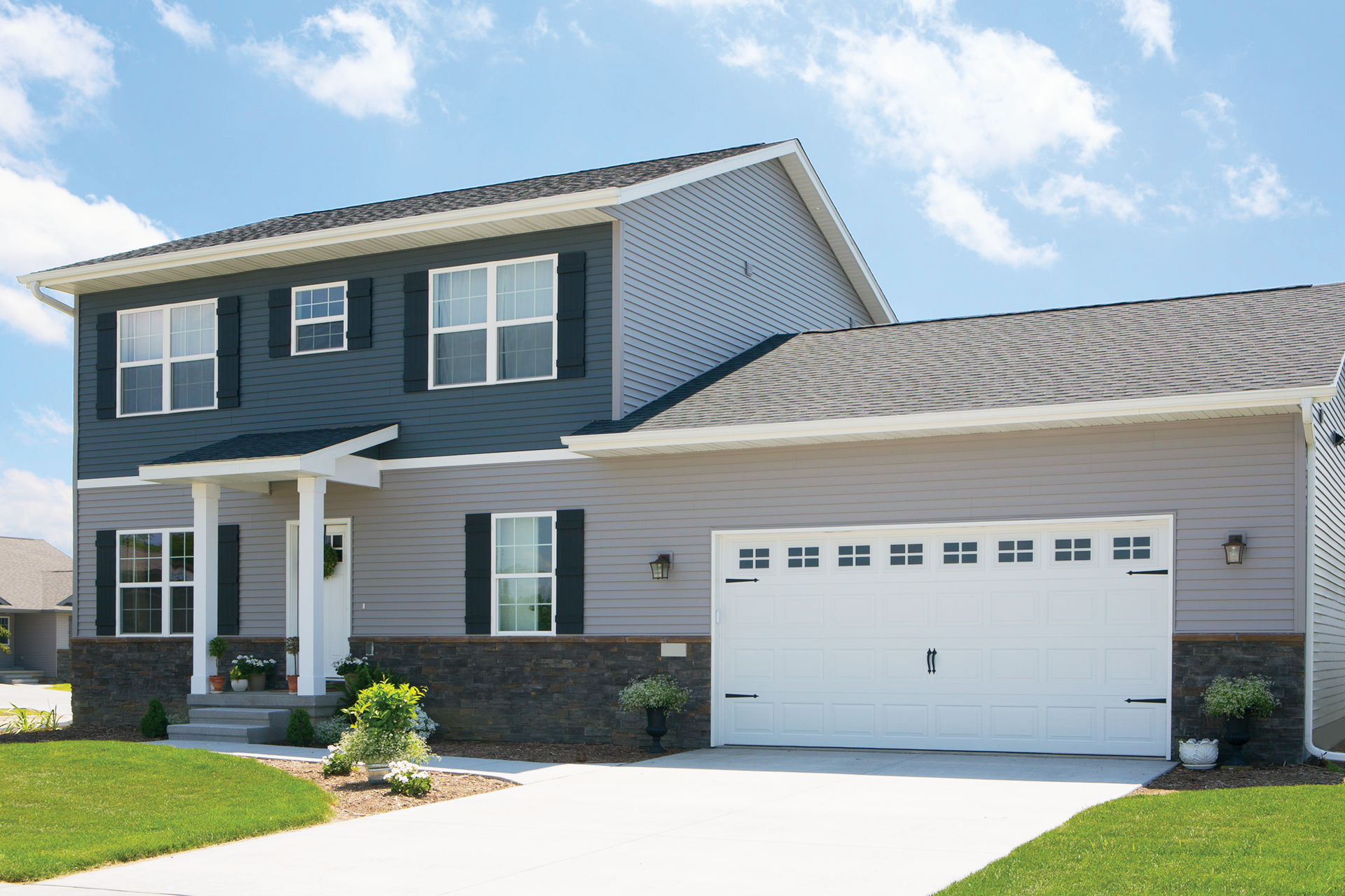 A large house with a white garage door and black siding