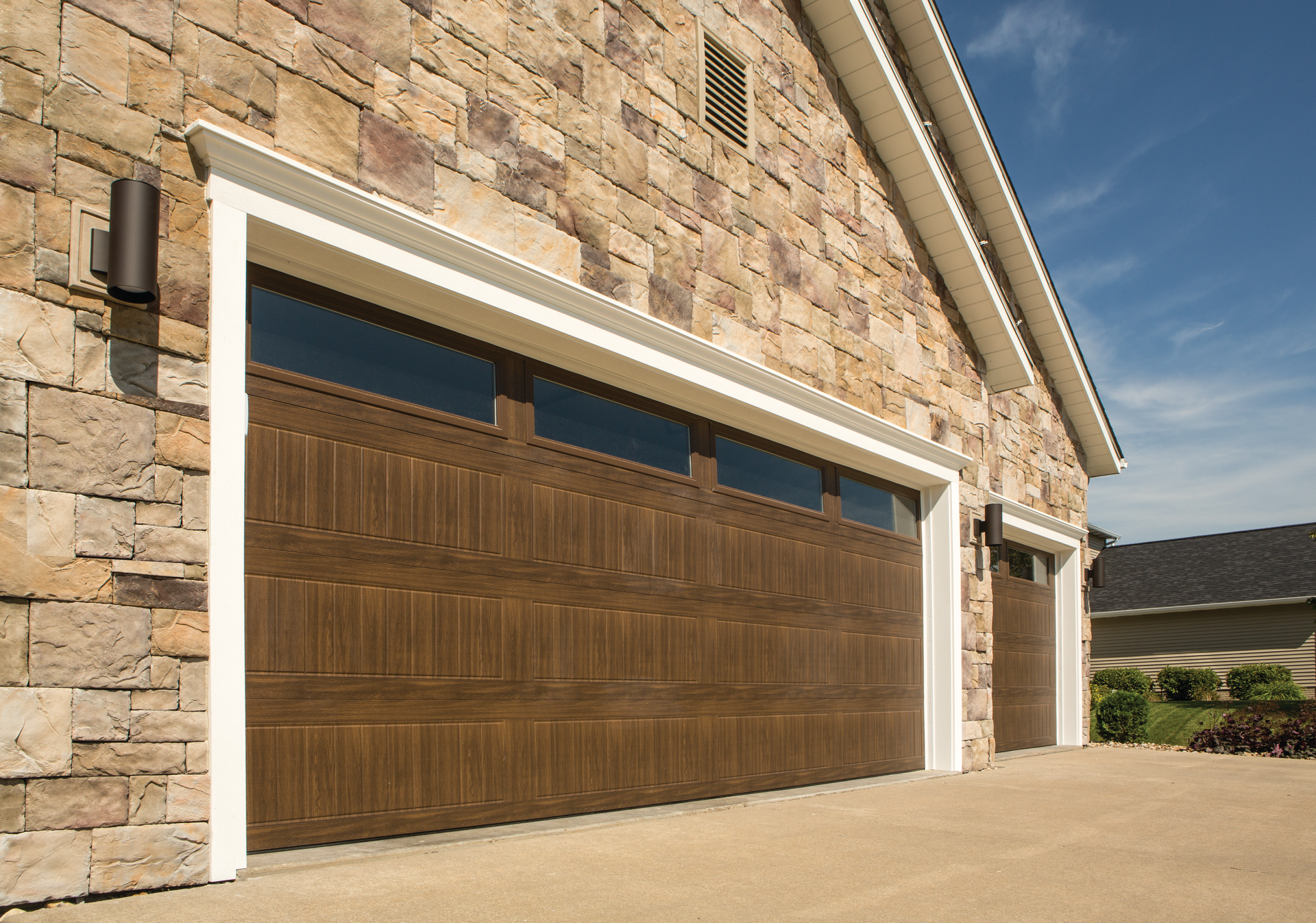 A stone building with two brown garage doors on it.