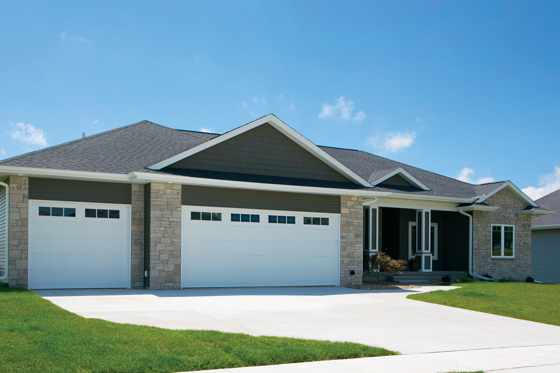 A house with three white garage doors and a concrete driveway