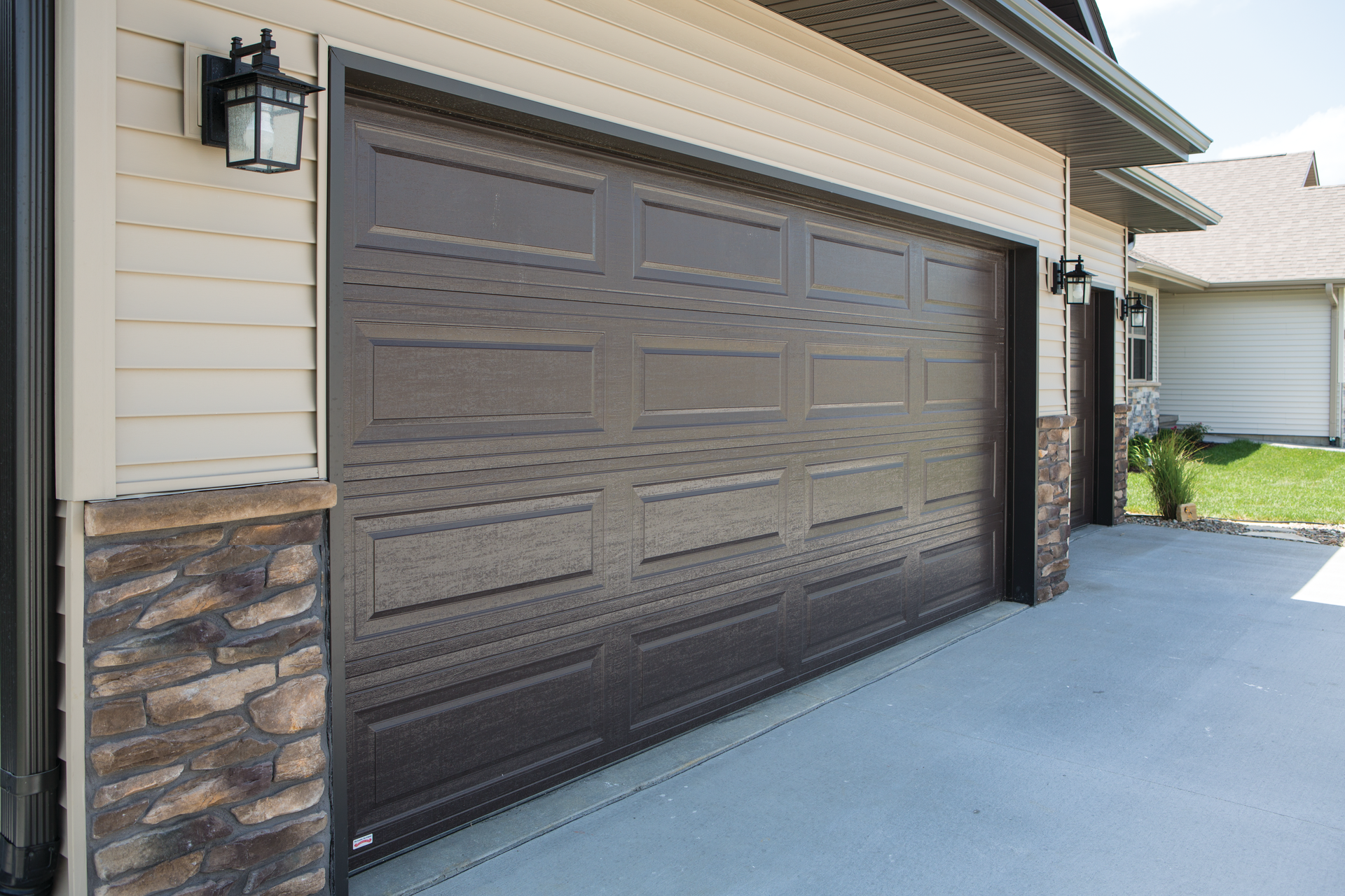 A large brown garage door is on the side of a house.