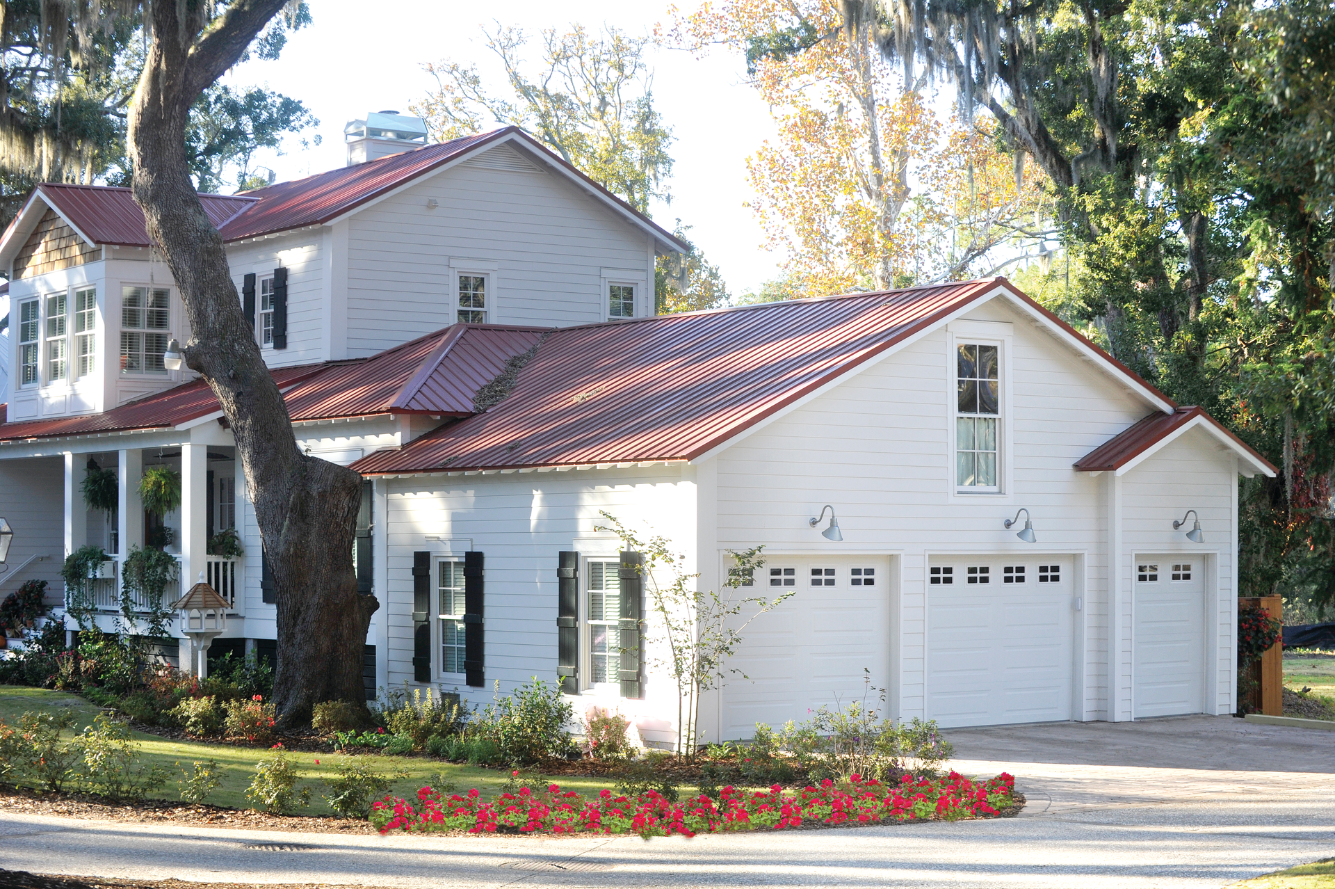 A white house with a red roof and three garage doors