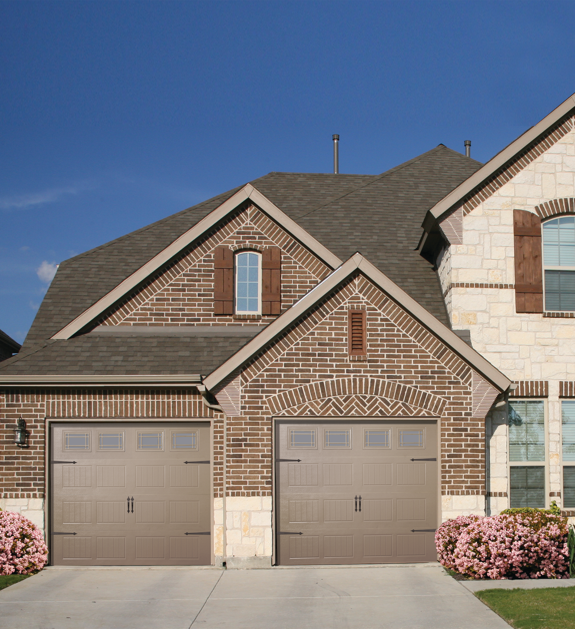 A house with two garage doors and a blue sky in the background