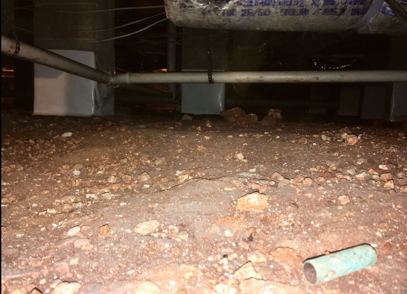 Dirt crawl space with pipes and a green pipe fragment.