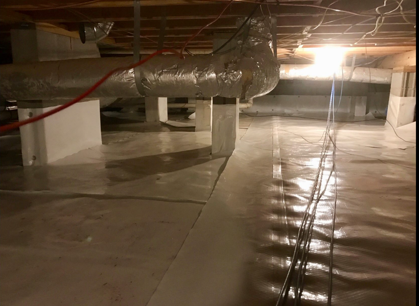 Crawl space with white vapor barrier, support pillars, ductwork, and electrical wiring.
