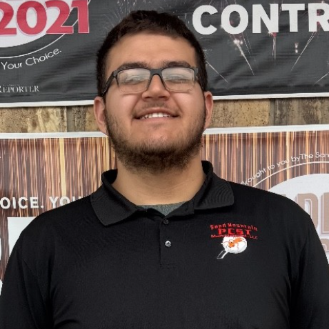 Man with glasses and a beard wearing a black polo shirt, smiling at the camera.
