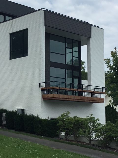 Modern white brick house with large windows and a small balcony.