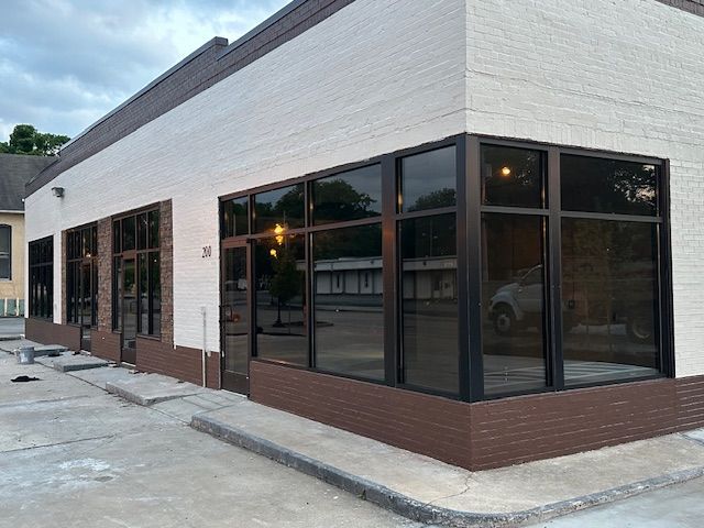 Exterior of a corner building with large windows, brown and white brick facade, and a dark-tinted glass.