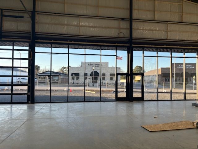 Inside a large building with glass walls, view of a building across the street.