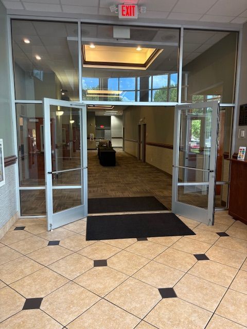 Glass doors open into a commercial building lobby, tiled floor.