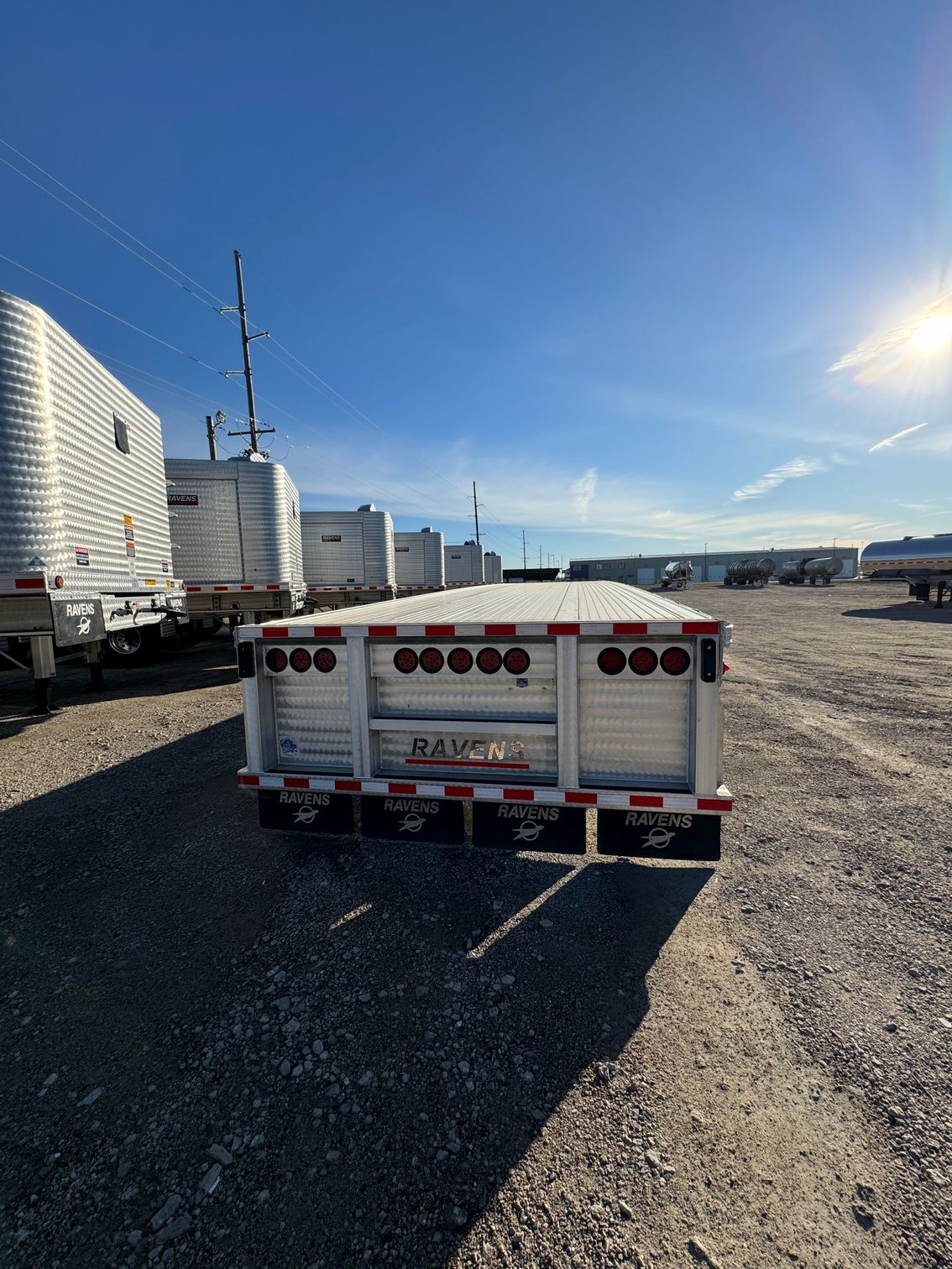 A white trailer is parked in a gravel lot