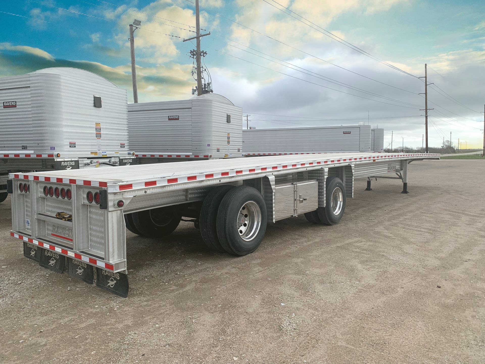 A flatbed trailer is parked in a dirt lot.