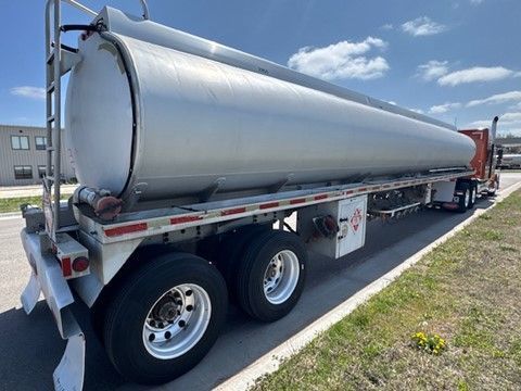 A semi truck with a large tank on the back is parked on the side of the road.