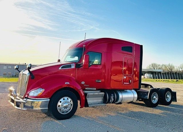 A red semi truck is parked in a parking lot.