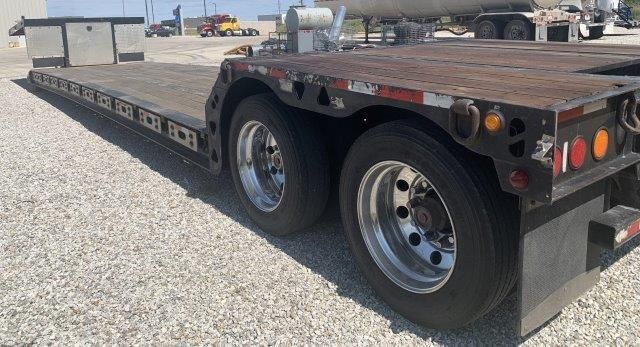 A flatbed trailer is parked in a gravel lot.