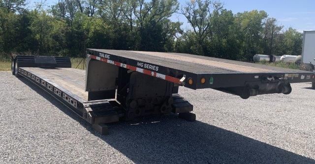 A flatbed trailer is parked on the side of the road.