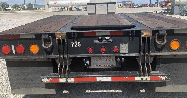 The back of a semi truck with a wooden bed is parked in a parking lot.