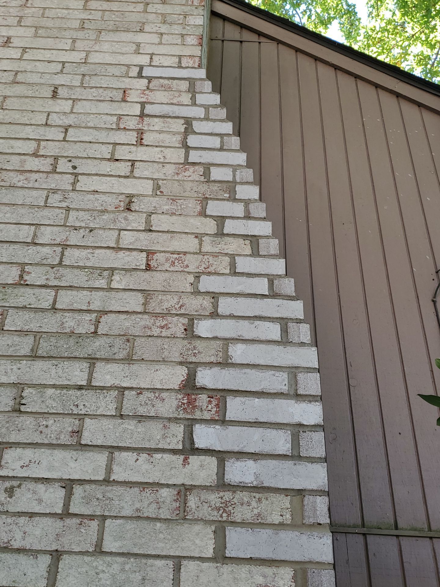 Brick chimney adjoins brown siding on a building, a zig-zag shape to the side.