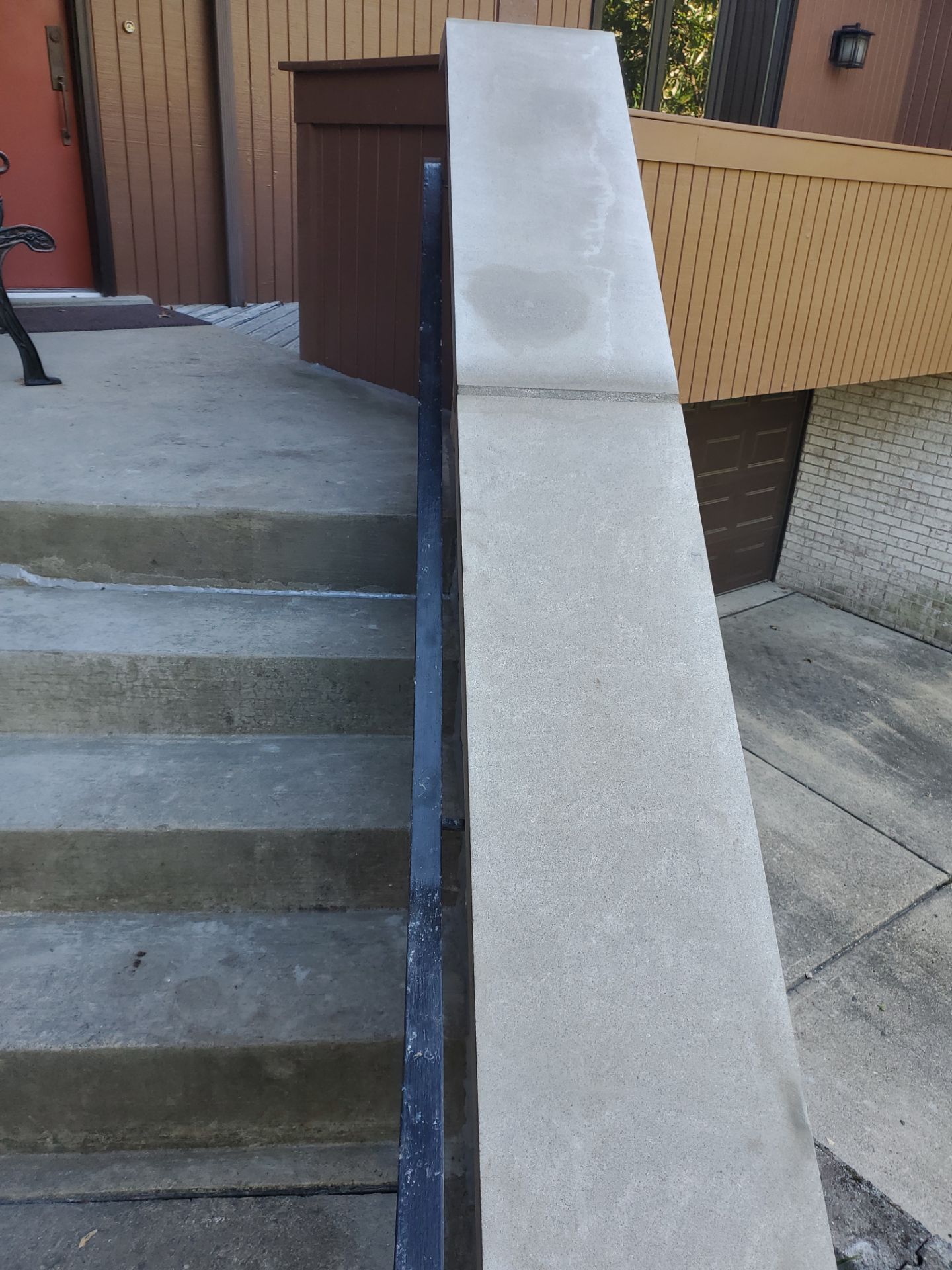 Concrete steps leading up, with a concrete and black railing.